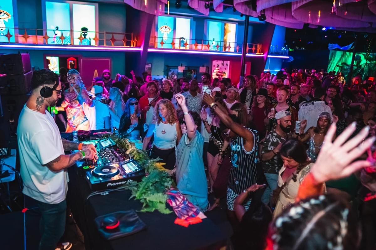 DJ performing for a lively crowd dancing at a company holiday party celebration.