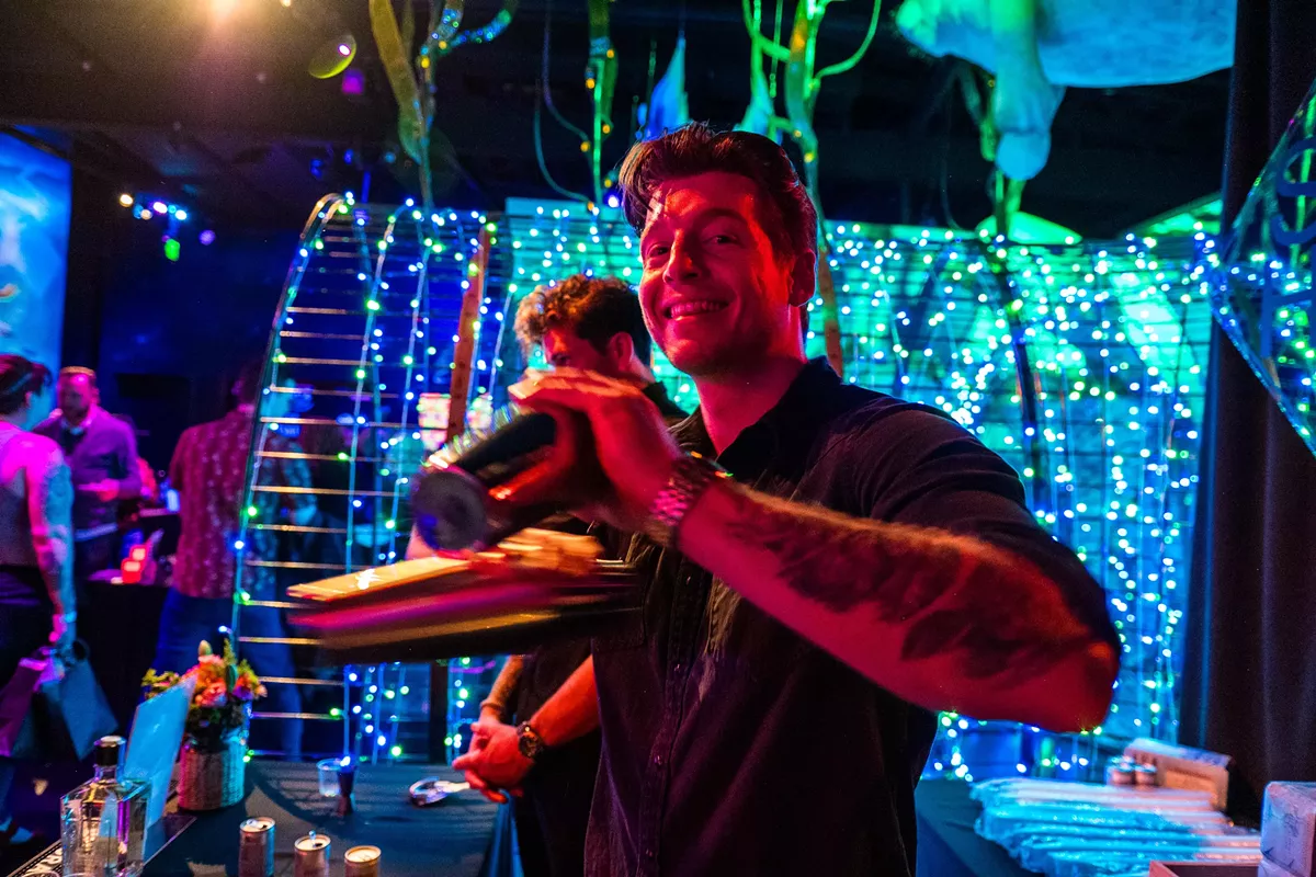Bartender mixing cocktails for guests at a corporate holiday party.