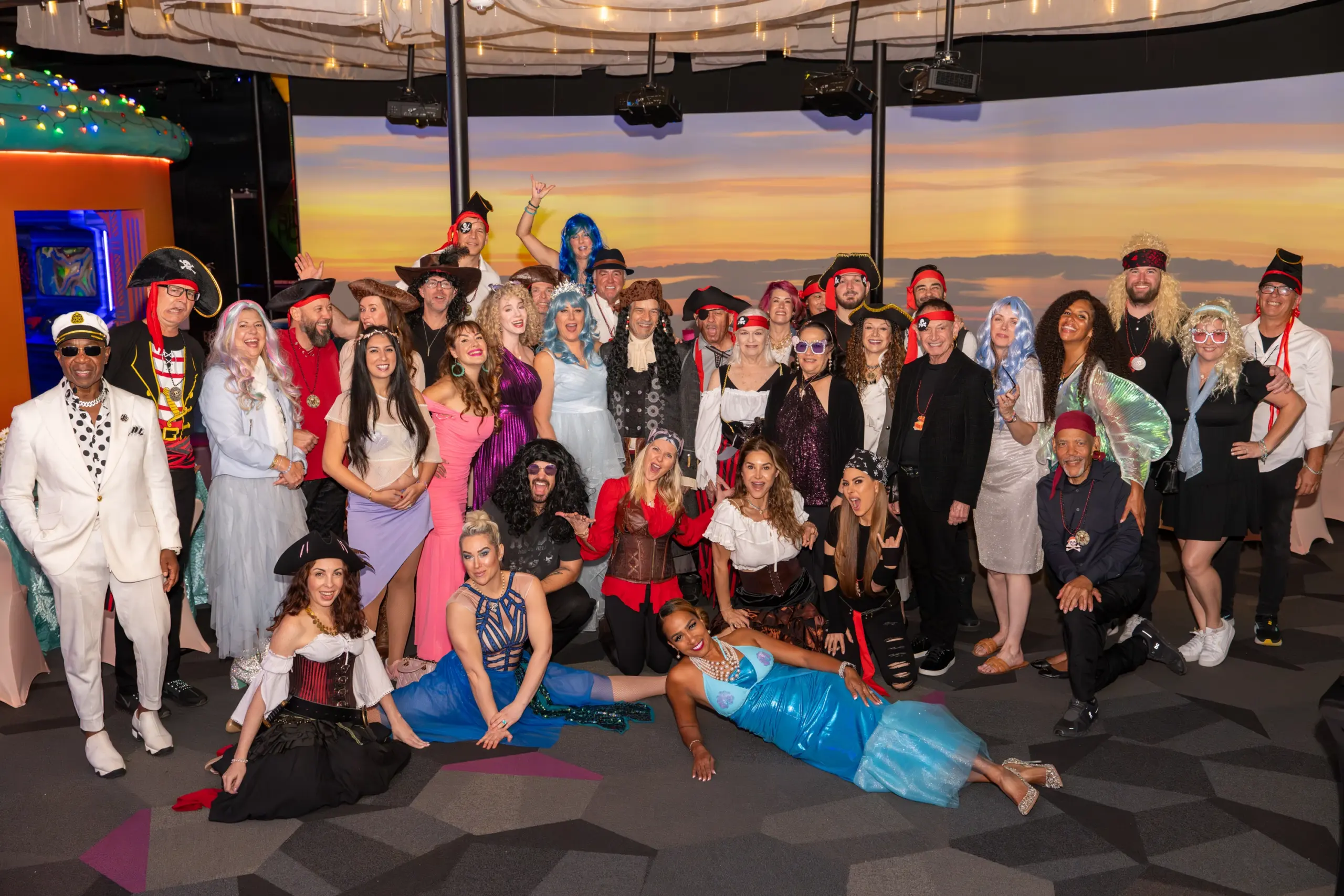 Large group of adults in colorful costumes and pirate attire posing in an immersive art space
