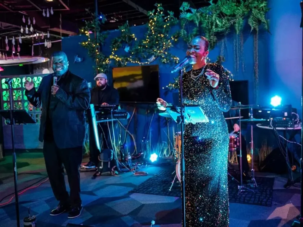 A live band performs in FloridaRAMA as an immersive events venue with blue lighting and decorative greenery
