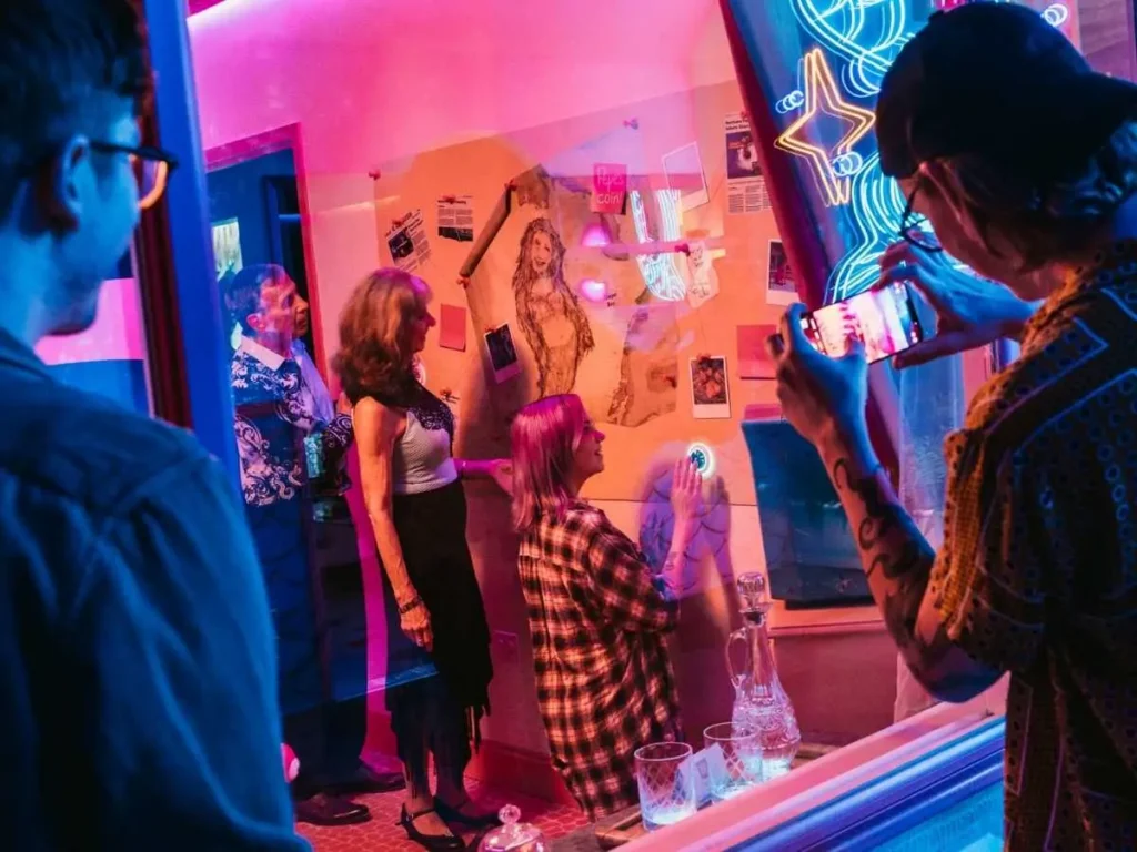 Visitors interact with a neon-lit immersive art installation featuring a wall of clues and interactive elements
